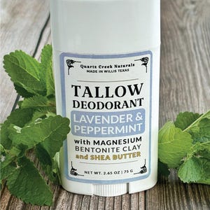 K&ouml;nnte beinhalten: Ein wei&szlig;er Deodorant-Stick aus Kunststoff mit einem Etikett, das Quartz Creek Naturals, Tallow Deodorant, Lavender & Peppermint with Magnesium, Bentonite Clay and Shea Butter, 75 g beschriftet ist. Das Etikett zeigt schwarzen und blauen Text.