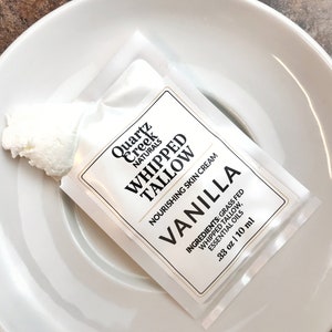 May include: A white rectangular sample packet of Quartz Creek Naturals Whipped Tallow Vanilla nourishing skin cream. The label lists ingredients as grass fed whipped tallow and essential oils, with a volume of .33 oz | 10 ml.