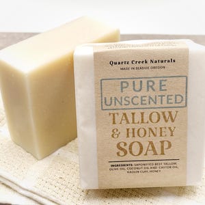 May include: A bar of pure unscented tallow and honey soap from Quartz Creek Naturals, made in Seaside, Oregon. The soap is wrapped in white paper with brown text and ingredients listed on the label.