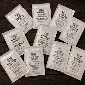 May include: A collection of nine white rectangular sample packets of Quartz Creek Naturals whipped tallow nourishing skin cream. Each packet features black text listing the brand, product name, scent, and a volume of .33 oz | 10 ml.
