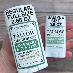 K&ouml;nnte beinhalten: Zwei wei&szlig;e Deodorant-Sticks mit der Aufschrift Quartz Creek Naturals Tallow Deodorant Rosemary & Tea Tree. Der gr&ouml;&szlig;ere Stick ist mit REGULAR/FULL SIZE 75 G und der kleinere mit SAMPLE SIZE 14.2 G gekennzeichnet, beide mit Magnesium, Bentonit-Ton und Sheabutter.