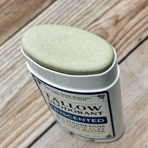 K&ouml;nnte beinhalten: Ein ovaler Stick aus unparf&uuml;miertem Talg-Deodorant in blassgr&uuml;ner Farbe. Der wei&szlig;e Kunststoffbeh&auml;lter tr&auml;gt ein Etikett mit dem Text Quartz Creek Naturals, Tallow Deodorant, Unscented, with Magnesium, Bentonite Clay, and Shea Butter.