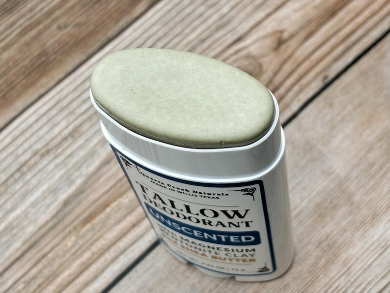 K&ouml;nnte beinhalten: Ein ovaler Stick aus unparf&uuml;miertem Talg-Deodorant in blassgr&uuml;ner Farbe. Der wei&szlig;e Kunststoffbeh&auml;lter tr&auml;gt ein Etikett mit dem Text Quartz Creek Naturals, Tallow Deodorant, Unscented, with Magnesium, Bentonite Clay, and Shea Butter.