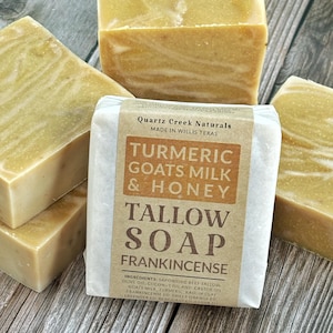 May include: Four rectangular bars of golden-yellow tallow soap with a marbled texture. One bar is wrapped in a tan paper label reading Quartz Creek Naturals, Turmeric Goats Milk & Honey, Tallow Soap, Frankincense, and a list of ingredients.