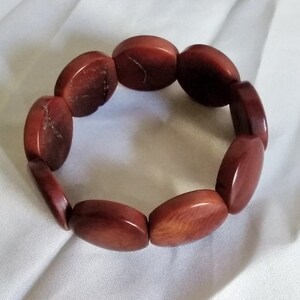 May include: A red brown bracelet made of oval-shaped beads.
