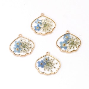 May include: Four gold-toned metal charms with a scalloped edge, each featuring a clear resin filled with pressed blue and white flowers.
