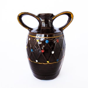 May include: A brown ceramic vase with two handles and a diamond pattern. The vase is decorated with colorful dots.