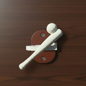 May include: A baseball-themed door handle with a white bat and ball design. The handle is mounted on a brown leather-like backing with a white bracket. The background is a dark brown wooden surface.
