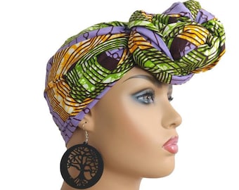 May include: A purple, green, and yellow patterned head wrap tied in a knot on top of a mannequin's head. The mannequin is wearing large, round, black earrings with a tree design.