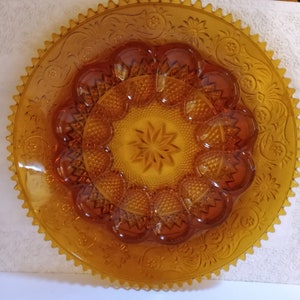 May include: Amber glass serving dish with a scalloped edge and a raised, starburst design in the center. The dish has 12 individual compartments around the center.