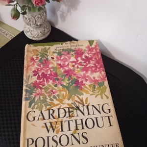 Może przedstawiać: Antyczna książka zatytułowana "Gardening Without Poisons" autorstwa Beatrice Trum Hunter. Okładka przedstawia akwarelowy obraz różowych kwiatów z zielonymi liśćmi.