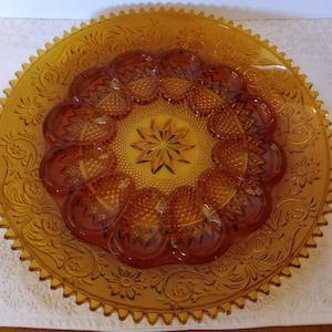 May include: Amber glass serving dish with a scalloped edge and a raised, star-shaped design in the center. The dish has 12 individual compartments around the center.