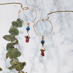 Dangly charm hoop earrings in 14k gold filled with natural red garnet and dark tourmaline gemstones. Handmade dainty minimalist jewelry