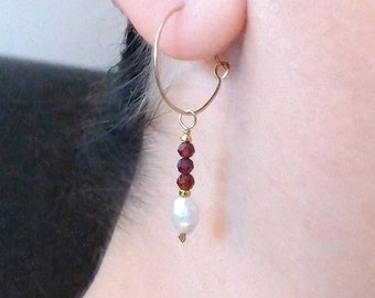 May include: Gold hoop earrings with a dangling pearl and red gemstone beads.