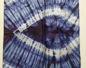 May include: A blue and white tie-dye fabric with a circular pattern. The fabric is folded in half and the pattern is symmetrical.