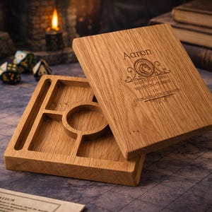 May include: A wooden dice tray and lid set with engraved text. The tray has compartments and a circular area. The lid is engraved with a name and decorative text. The wood has a natural grain and warm tones.