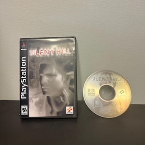 Peut inclure: Boîtier et disque de jeu PlayStation pour "Silent Hill". Le boîtier noir affiche le titre du jeu en blanc et une image en niveaux de gris. Le disque présente le titre du jeu et le logo PlayStation.