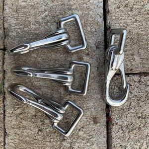 May include: Three silver metal snap hooks with a rectangular loop and a single hook. One silver metal snap hook with a single hook.