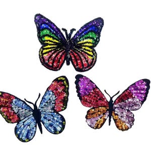 May include: Three colorful butterfly patches with sequin details. The top butterfly features rainbow colors, while the other two have red, blue, purple, and gold hues. Each butterfly has a black outline and antennae, perfect for embellishing clothing or accessories.