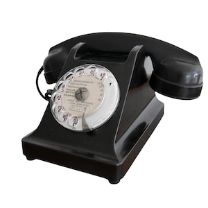 Może przedstawiać: Czarny telefon z tarczą numerową w stylu vintage, wyposażony w okrągłe pokrętło z przezroczystą plastikową osłoną. Środek tarczy zawiera francuski tekst, w tym Renseignements, Telegrammes, Police, Secours oraz Pompiers. Słuchawka spoczywa na podstawie.