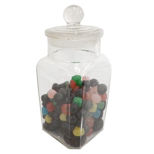 Peut inclure: Un bocal de pharmacie en verre transparent avec un couvercle, rempli de bonbons colorés. Les bonbons sont de différentes couleurs, dont le rouge, le vert, le jaune, le bleu, le rose et le noir. Le bocal a un bouchon en verre transparent.