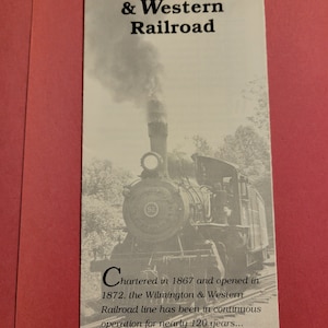 以下が含まれることがあります： 蒸気機関車の白黒写真。ページには「Wilmington & Western Railroad」と「Chartered in 1867 and opened in 1872, the Wilmington & Western Railroad line has been in continuous operation for nearly 120 years...」というテキストが印刷されています。
