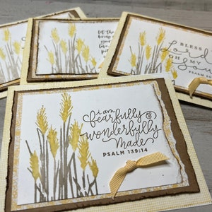 May include: Four handmade cards with a wheat field design and inspirational quotes. The cards feature a brown and yellow wheat field design with a white background. The quotes are "Bless the Lord Oh My Soul Psalm 103:1", "Let the beauty of the Lord your God be upon you", "I am fearfully and wonderfully made Psalm 139:14", and "I am fearfully and wonderfully made Psalm 139:14".