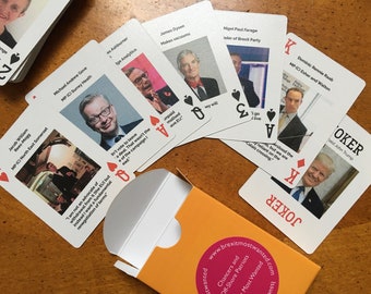 May include: A deck of playing cards featuring images of British politicians with their names and quotes. The cards are arranged in a fan shape on a wooden table. The Joker card features a picture of Donald Trump with the text "JOKER" and "Donald John Trump".