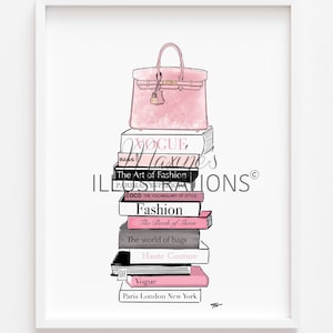 May include: A framed illustration of a pink handbag resting on a pile of fashion books. The titles include "Vogue," "Fashion," and "Haute Couture." The artwork has a minimalist style with a white background and a focus on the accessories.