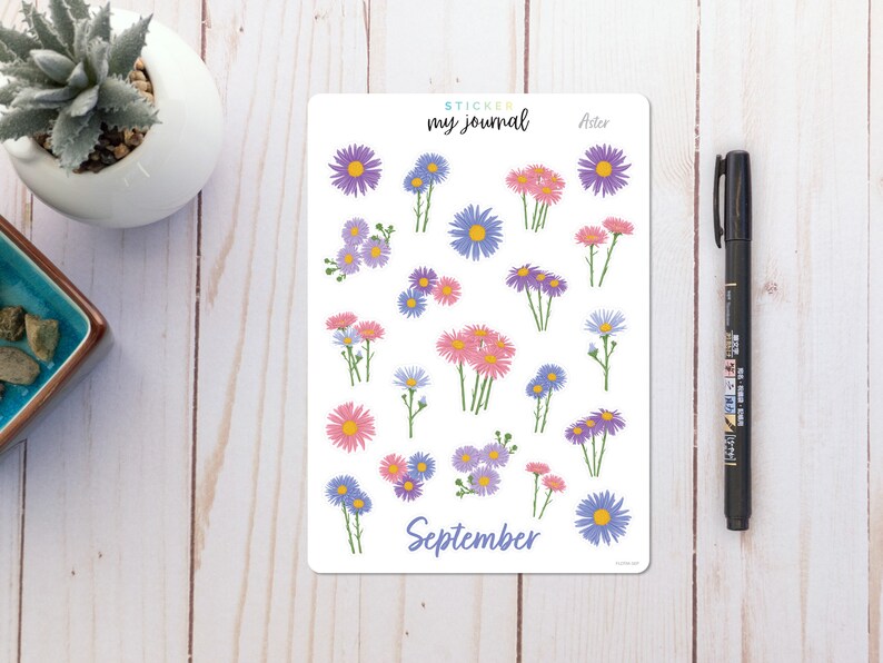 May include: A sheet of stickers featuring purple, pink, and blue aster flowers with green stems. The stickers are labeled "Sticker my journal" and "Aster". The sheet also includes the word "September".