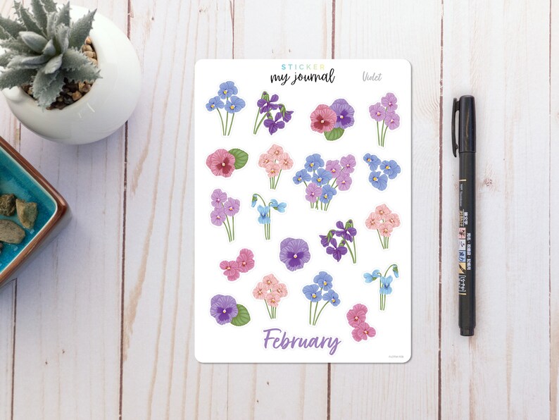 May include: A sheet of stickers featuring violet flowers in various shades of purple, pink, and blue. The stickers are labeled "Violet" and "February" and are designed for use in a journal.