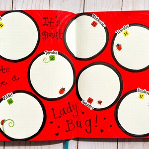 May include: A red planner with black circles and the text "It's great to be a Lady Bug!"  Each circle has a day of the week and a number, from Monday 11th to Sunday 17th.  There are ladybugs and green vines drawn on the page.