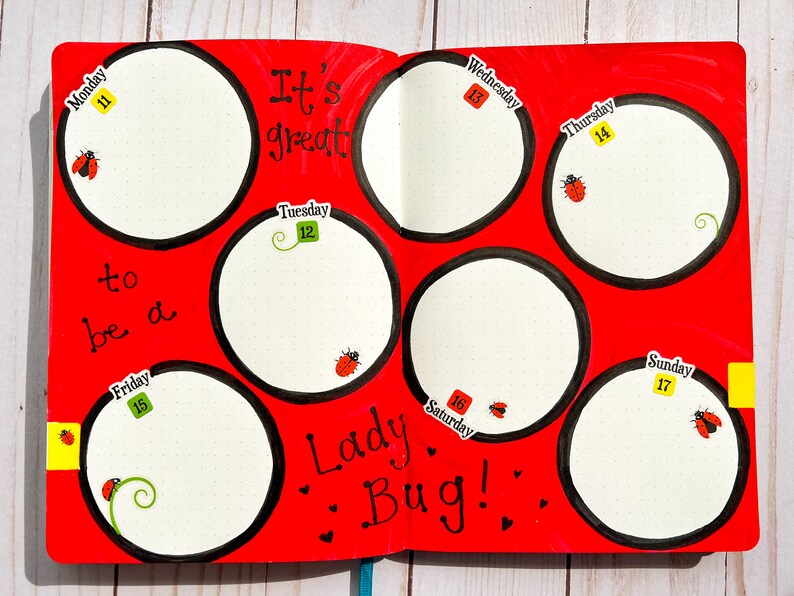 May include: A red planner with black circles and the text "It's great to be a Lady Bug!"  Each circle has a day of the week and a number, from Monday 11th to Sunday 17th.  There are ladybugs and green vines drawn on the page.