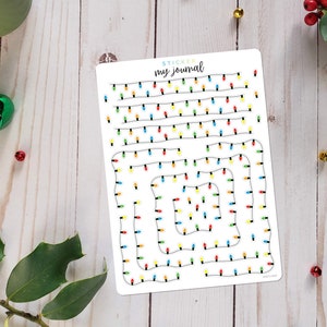 May include: A sheet of stickers featuring various designs of Christmas lights. The stickers are white with black outlines and feature colorful lights in red, yellow, blue, and green.