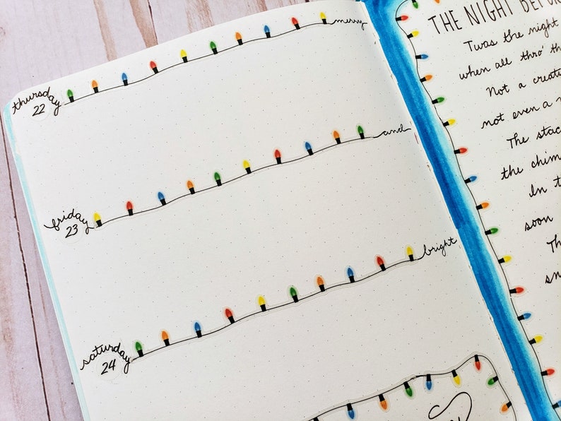Puede incluir: Una p&aacute;gina de diario con l&iacute;neas negras dibujadas a mano y bombillas navide&ntilde;as de colores. El texto incluye Thursday 22, Friday 23, Saturday 24 y el poema The Night Before Christmas escrito en tinta negra con un borde de acuarela azul.