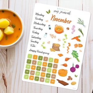 May include: A sticker sheet with a calendar for November, a list of days of the week, and the words "Sticker my journal" and "Happy Thanksgiving". The sheet features various Thanksgiving-themed illustrations, including a pot of soup, a turkey leg, carrots, onions, potatoes, and a bag of potatoes.
