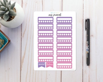 May include: A sheet of stickers with a gradient background in shades of pink and purple. The stickers are designed for journaling and feature blank spaces for writing and rows of small circles for tracking. The sheet includes the text "STICKER my journal" and the words "SUCCESS!" and "Believe" on two banners.