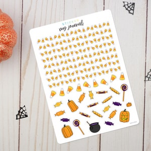 May include: A sheet of Halloween themed stickers featuring candy corn, pumpkins, lollipops, candy, and a cauldron. The sheet is white with the text "STICKER my journal" at the top.