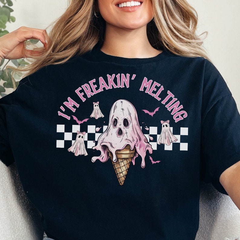 Puede incluir: Camiseta negra con un gr&aacute;fico rosa y blanco de un cono de helado derriti&eacute;ndose con forma de fantasma. El texto "I'm Freakin' Melting" est&aacute; escrito en un c&iacute;rculo rosa alrededor del fantasma.