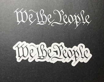 May include: Two white vinyl stickers with the phrase "We the People" in a stylized font. The stickers are on a black background.