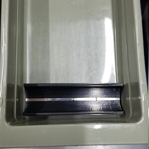 May include: A black plastic organiser with a built-in magnetic strip. The strip is made of several small, rectangular magnets.