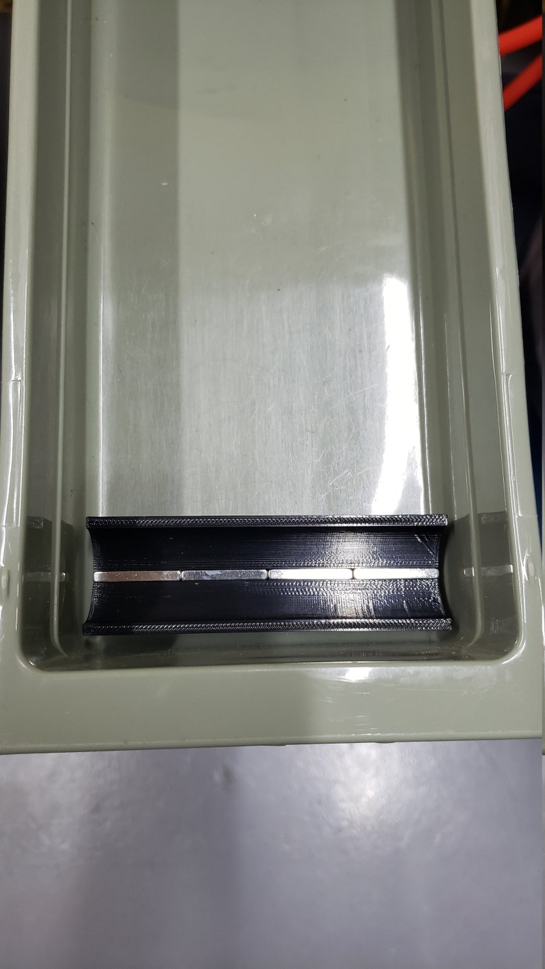 May include: A black plastic organiser with a built-in magnetic strip. The strip is made of several small, rectangular magnets.