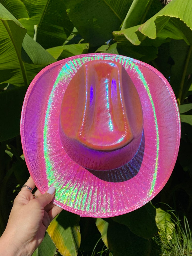 May include: A pink iridescent cowboy hat with a wide brim and a slightly pointed crown.