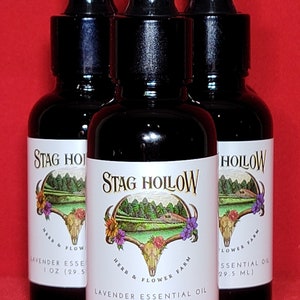 May include: Three amber glass bottles with black dropper tops and white labels. The labels feature a skull and crossbones logo with the text "Stag Hollow Herb & Flower Farm" and "Lavender Essential Oil 1 oz (29.5 ml)".