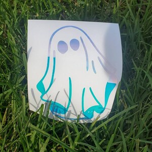 May include: A white ghost sticker with blue and purple accents. The ghost is outlined in blue and has two eyes.