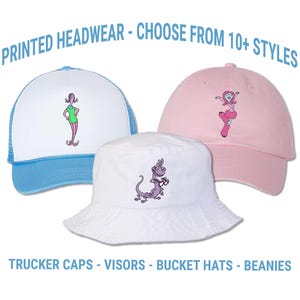 May include: Three hats with cartoon character designs. A white trucker hat with a blue brim, a pink baseball cap, and a white bucket hat. Text at the top says "PRINTED HEADWEAR - CHOOSE FROM 10+ STYLES". Text at the bottom says "TRUCKER CAPS - VISORS - BUCKET HATS - BEANIES".