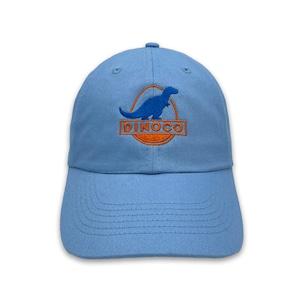 May include: Pale blue baseball cap with a curved peak. The cap has an embroidered orange and blue dinosaur design within an oval, with the word "DINOCO". The hat is made of a soft, durable fabric.