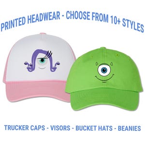May include: Two baseball caps with cartoon monster designs. One is pink and white with a purple monster eye design. The other is green with a blue monster eye design. Text on the image reads "PRINTED HEADWEAR - CHOOSE FROM 10+ STYLES" and "TRUCKER CAPS - VISORS - BUCKET HATS - BEANIES."
