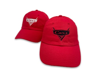 May include: Two red baseball caps with the word "Cars" embroidered on the front. The caps have a curved brim and a six-panel design. The logo is in a black and white design.