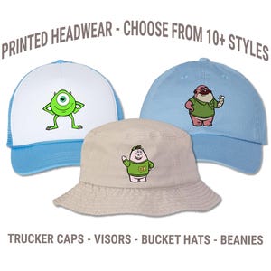May include: Three hats with cartoon character designs. A light blue trucker hat with a white front panel and a green one-eyed monster graphic. A light blue baseball cap with a cartoon character. A beige bucket hat with a cartoon character. Text: PRINTED HEADWEAR - CHOOSE FROM 10+ STYLES, TRUCKER CAPS - VISORS - BUCKET HATS - BEANIES.